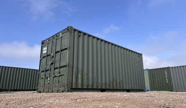 Low angle photo of a 20ft ex-hire green shipping container in outdoor yard on a clear day