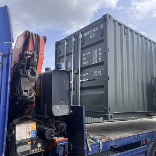 Close-up of a dark green container freshly secured on a blue HIAB lorry.